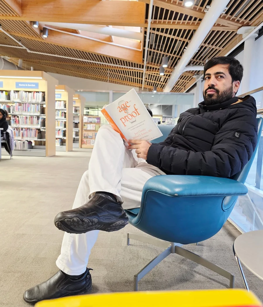 Faruukh Nadeem reading in a library, representing lifelong learning
